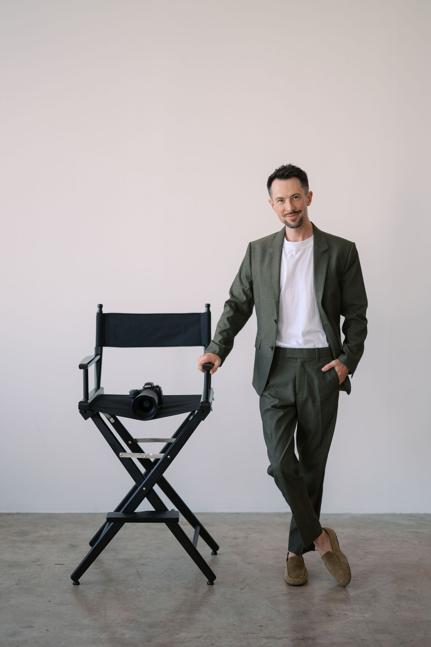 A sequence of images shows a person in a suit interacting with a black director's chair against a light gray background.
