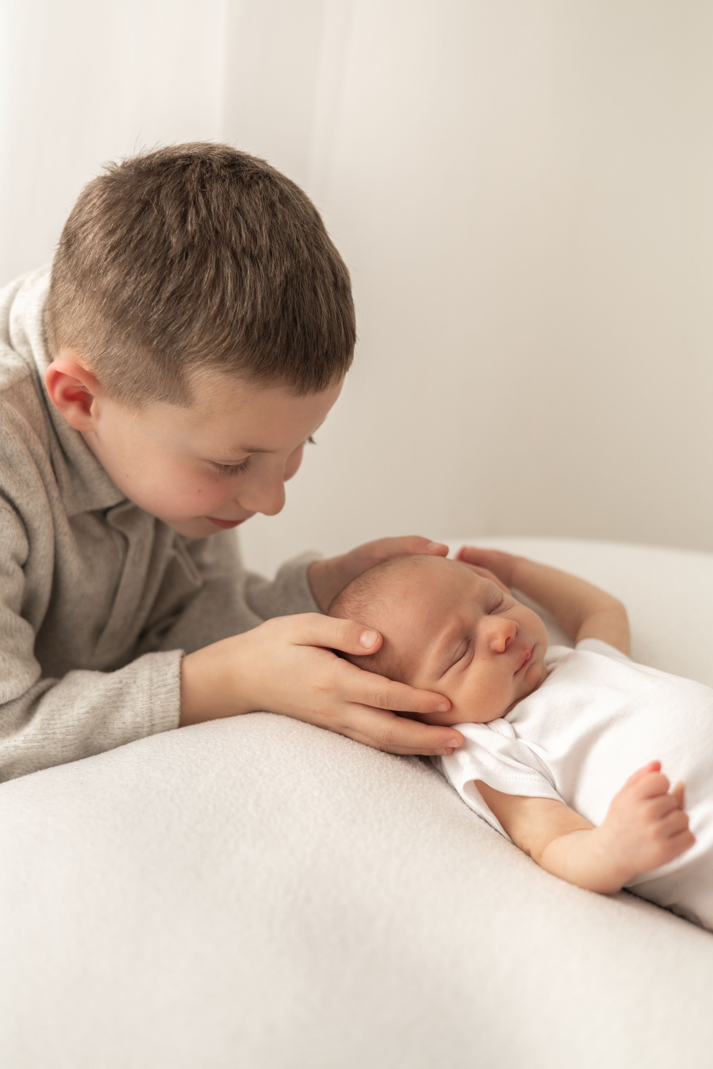 Natural baby photography Nottingham older sibling gently cradling sleeping newborn
