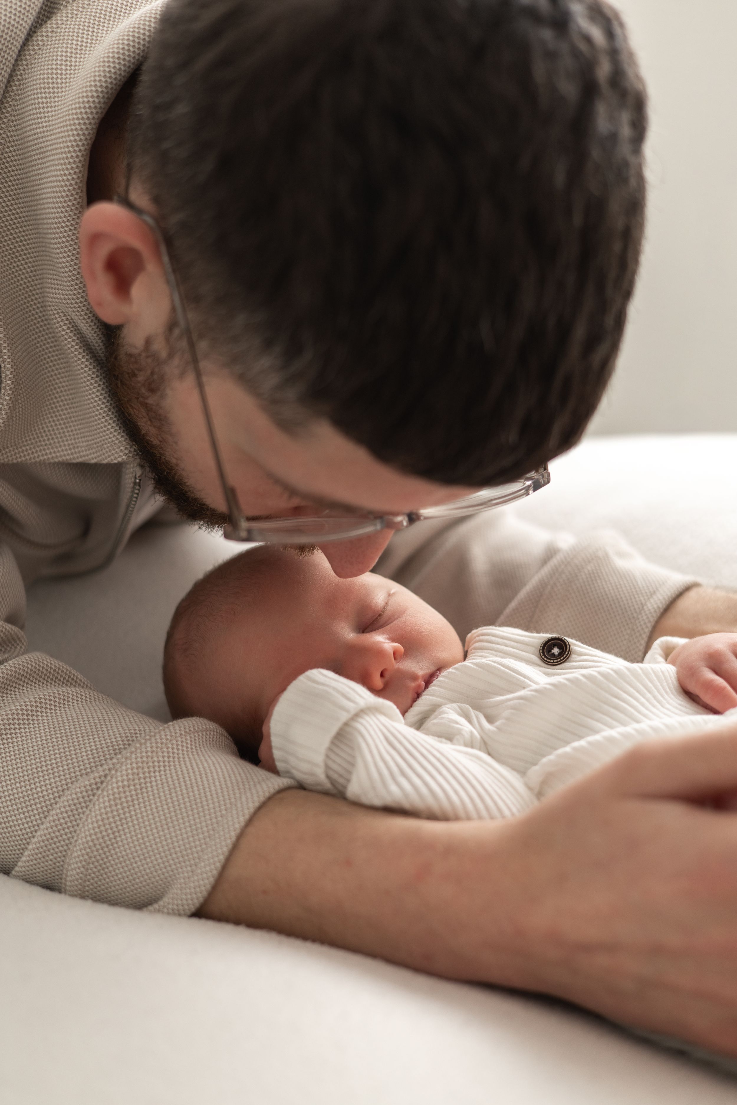Newborn photoshoot Nottingham dad tenderly kisses his sleeping newborn baby