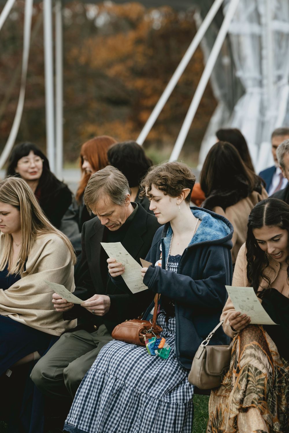 A group of people looking down at their mobile phones while sitting together in a crowded space.