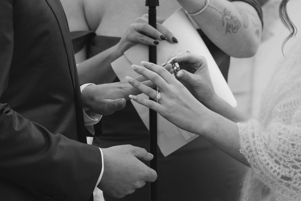 A series of black and white photos showing hands writing and signing documents during a wedding ceremony.
