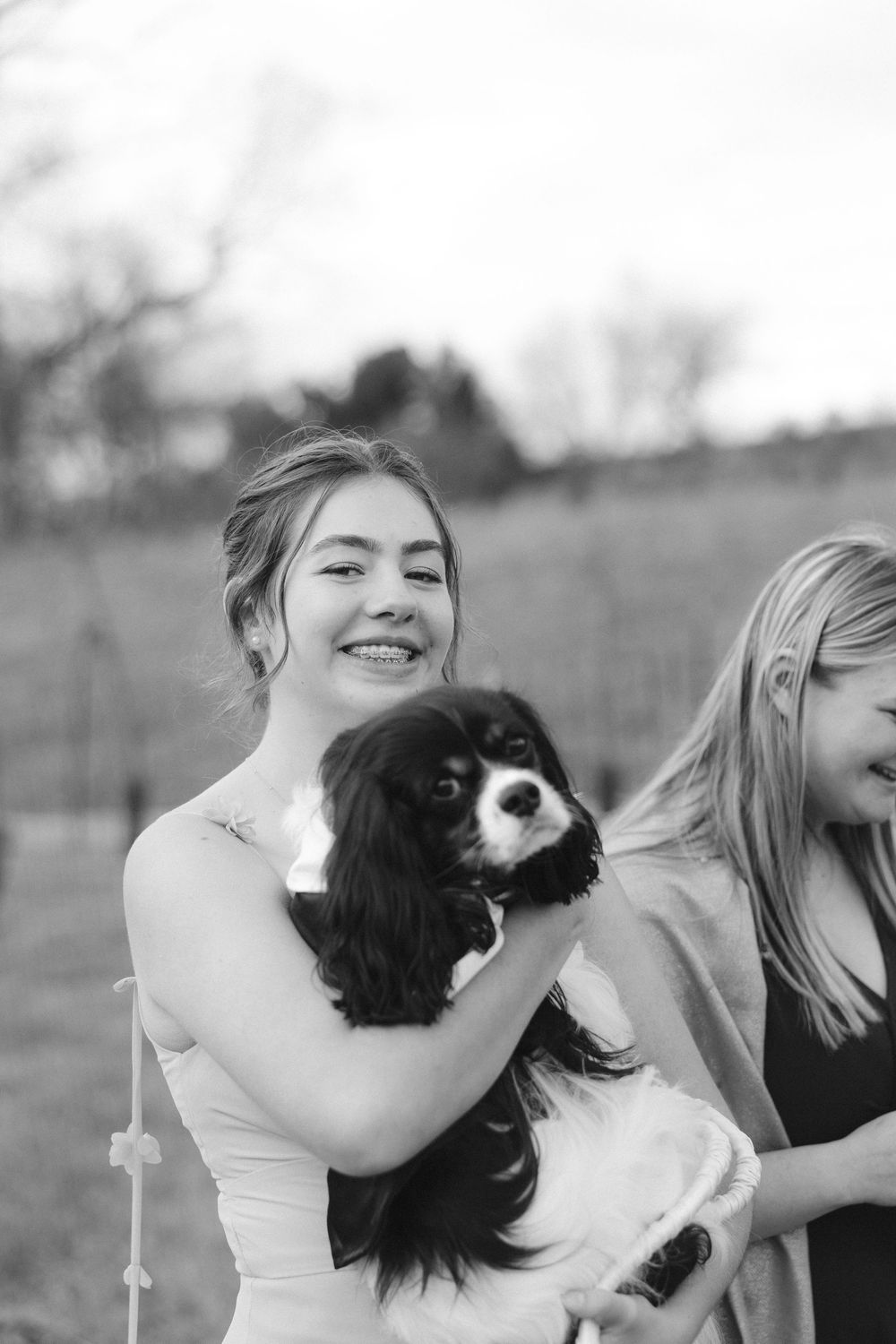 A playful black and white photo sequence showing a person joyfully interacting with a small dog outdoors.