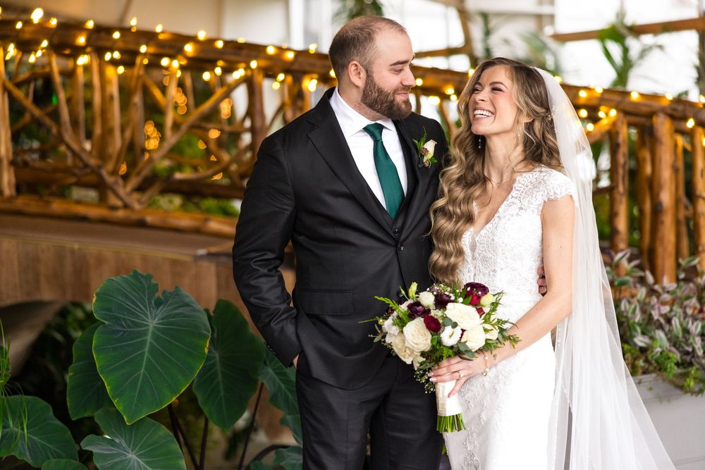 A joyful couple shares a romantic moment together during their wedding celebration at a rustic venue with greenery.