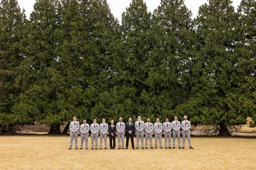 A panoramic sequence of people in white attire standing in a line against a backdrop of evergreen trees.