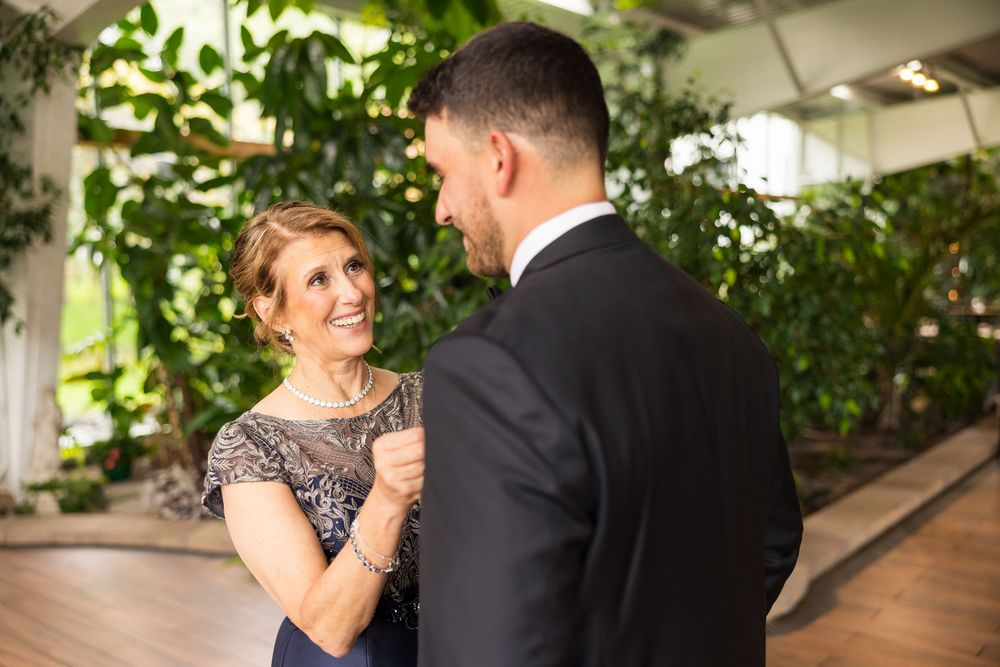 Couple shares a romantic dance moment in an elegant garden setting with lush greenery in the background.