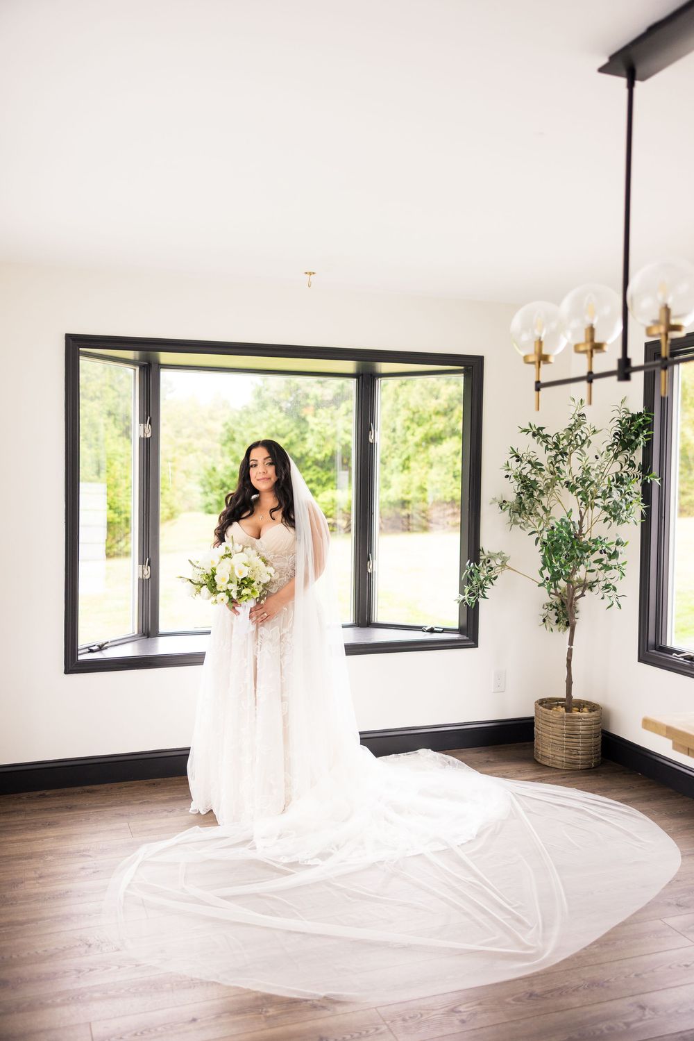 A flowing white veil dramatically swirls and billows in a modern room with large windows and hardwood floors.