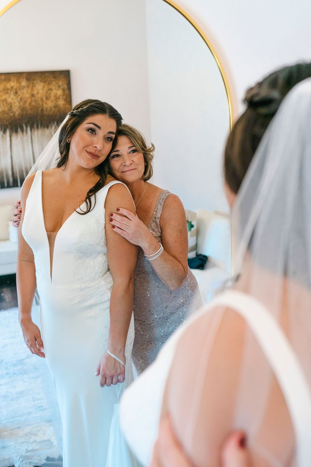 Wedding party getting ready scene with bridesmaids in silver dresses helping with final preparations.