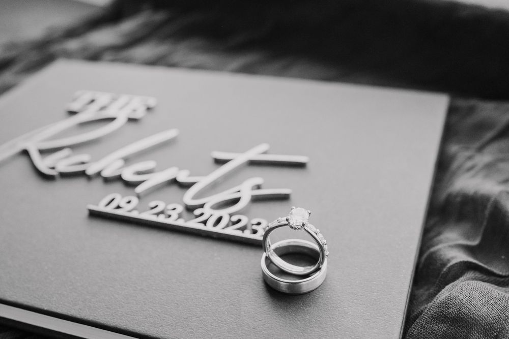 A series of black and white photographs showing decorative paper cutouts and wedding rings on a dark surface.