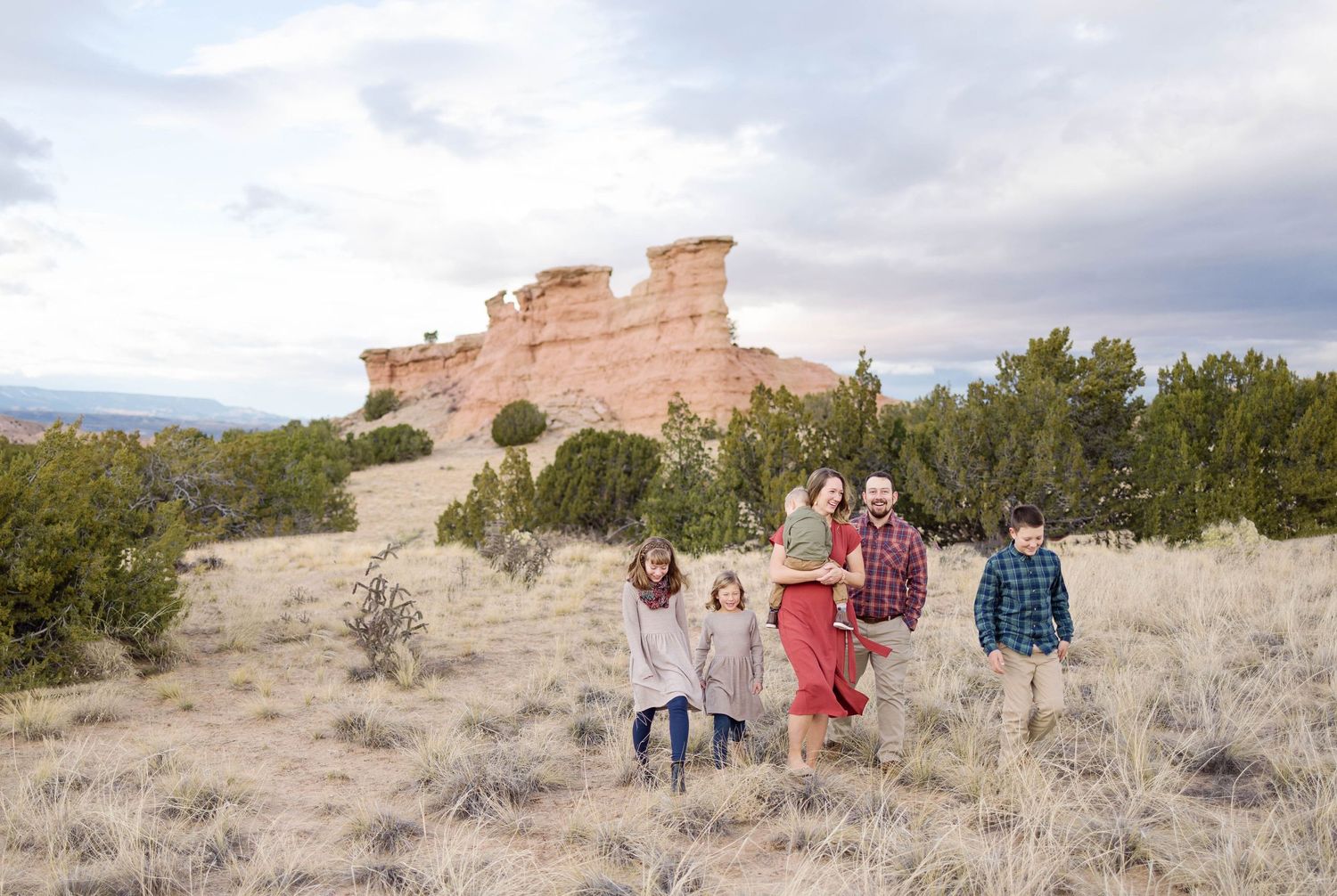 A group explores the sandy terrain beneath dramatic rock formations in the desert landscape.