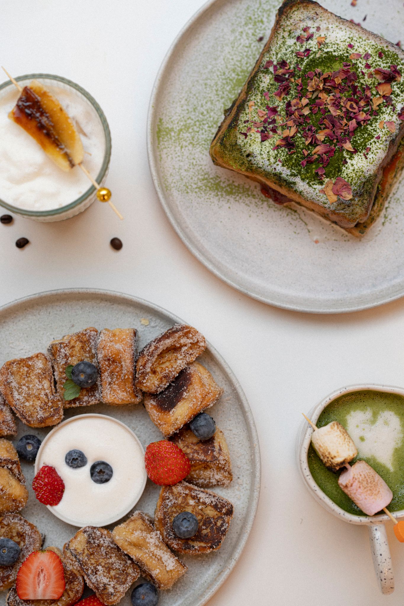 Elegant brunch spread featuring pastries with matcha toast, fresh berries, and creamy dipping sauce on ceramic plates.