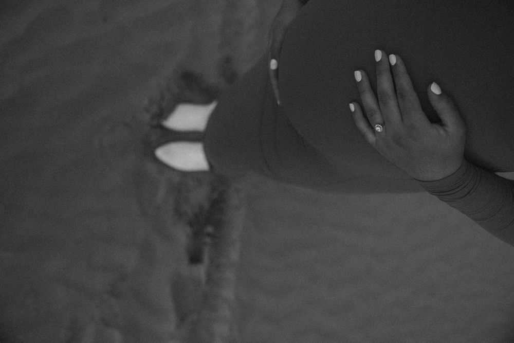Artistic black and white shot of hands cradling pregnant belly.