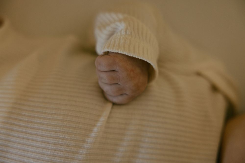 A newborn baby's tiny feet wearing a white knit hat.