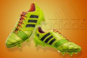 Bright neon yellow Adidas soccer cleats with black stripes against orange background.