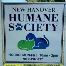 Sign for New Hanover Humane Society featuring blue and green cat and dog silhouettes with operating hours listed.