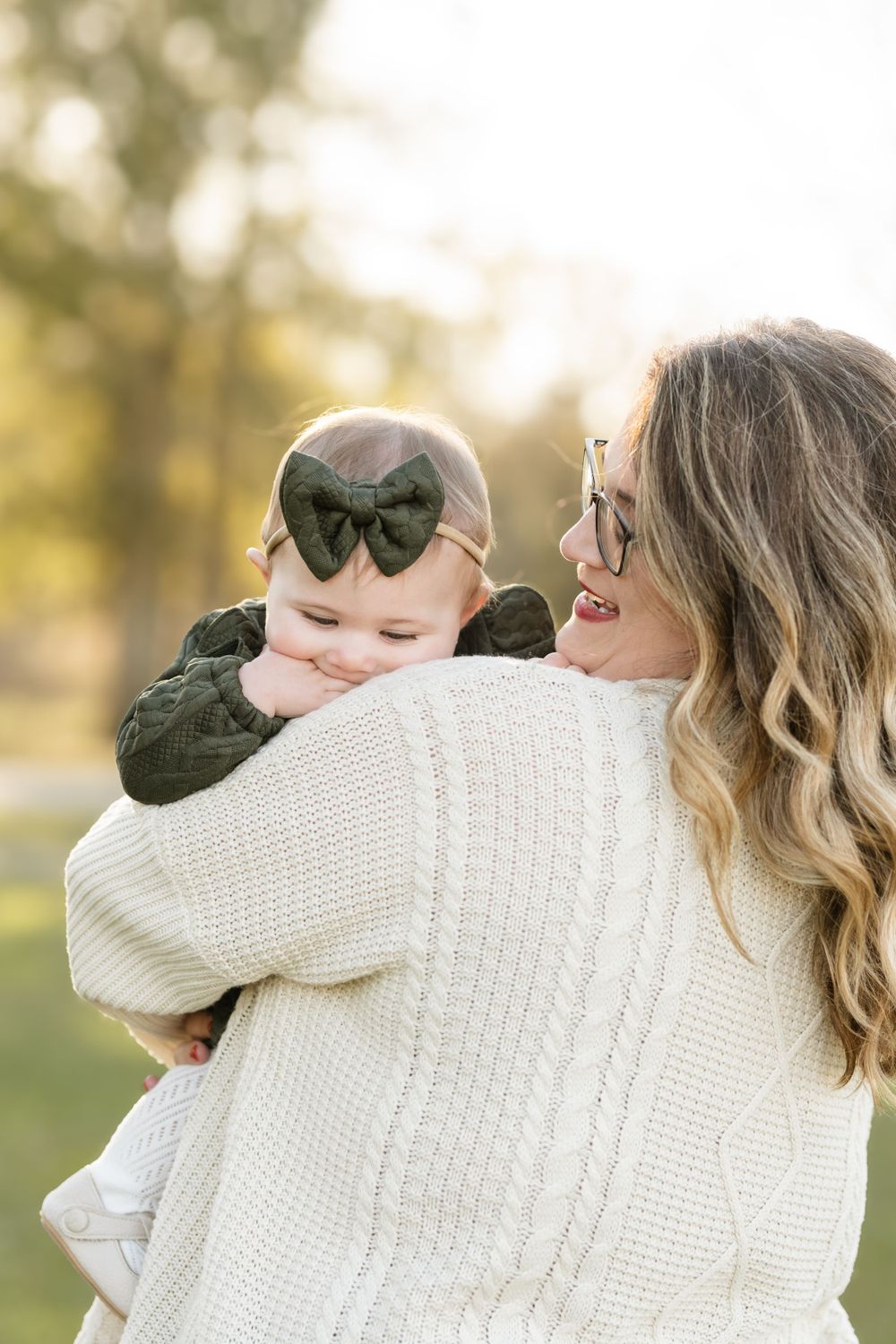 A tender outdoor moment captured from behind showing a cozy white knit sweater against a soft autumn backdrop.