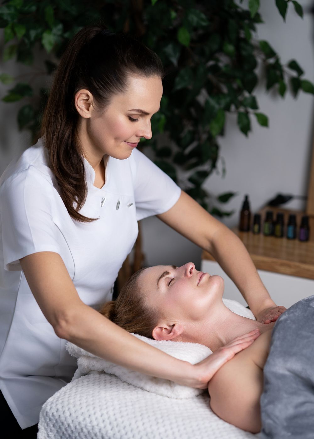 Professional massage therapist performs neck massage treatment on client at luxury spa.