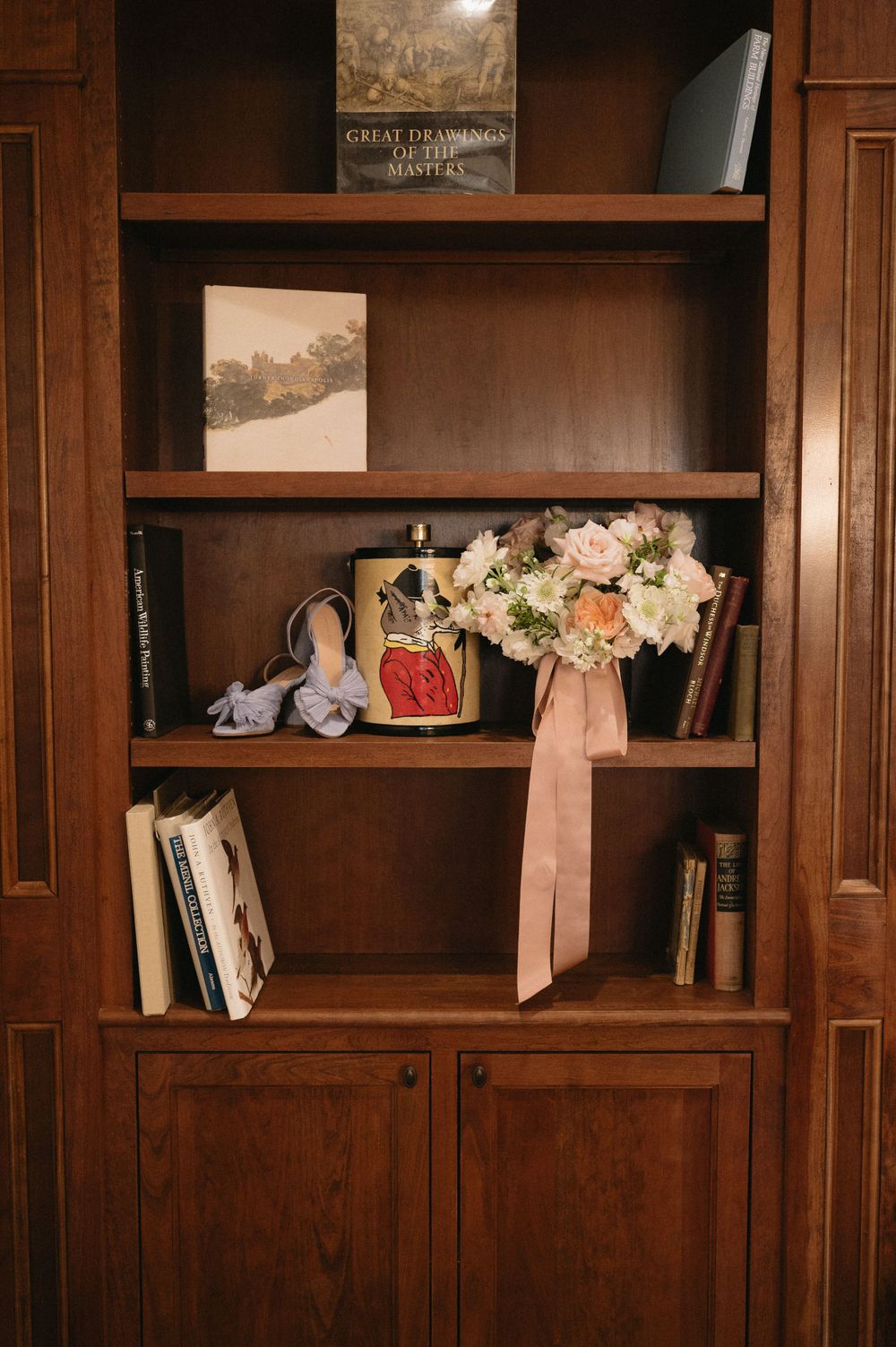 Wooden bookshelf with floral arrangements, books, and decorative items.