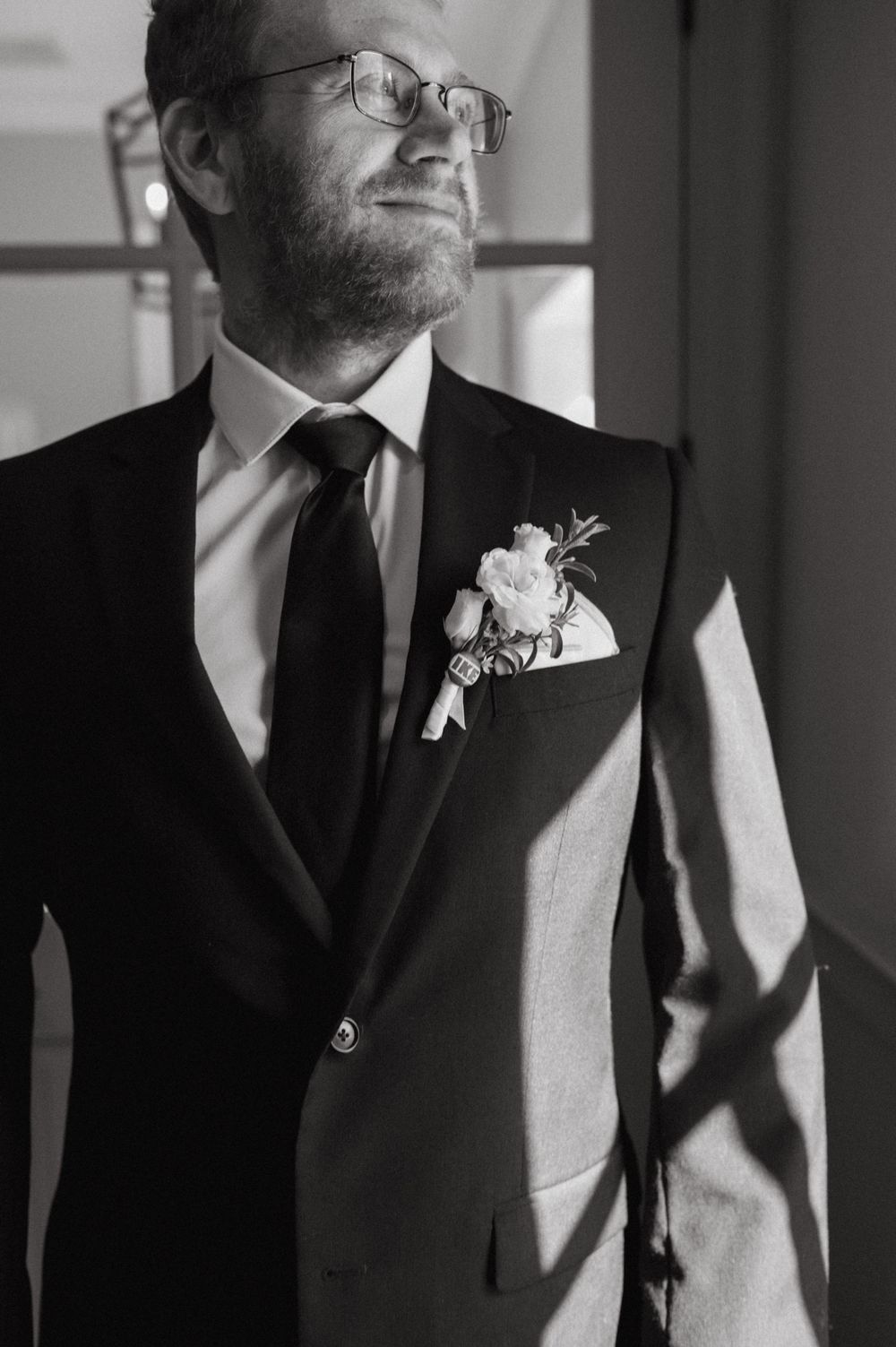 Classic black and white wedding attire with floral boutonniere detail.