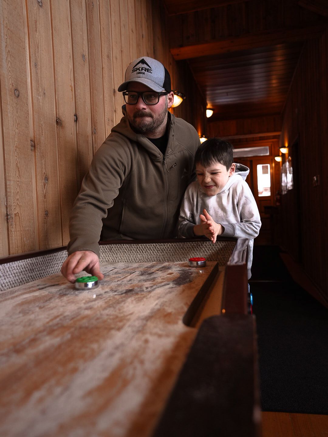People gathered around a rustic wooden table in a cabin interior.