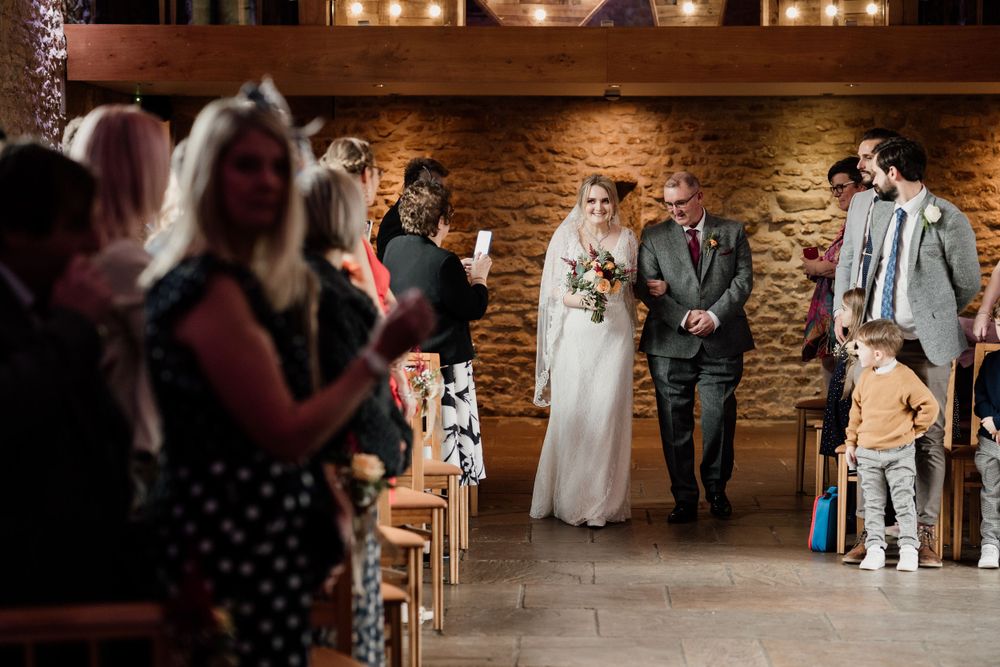 Wedding ceremony taking place in a rustic brick-walled venue with warm lighting.