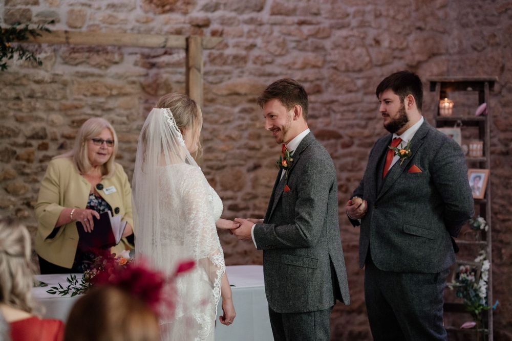 Wedding ceremony taking place in a stone-walled venue with elegant decor.