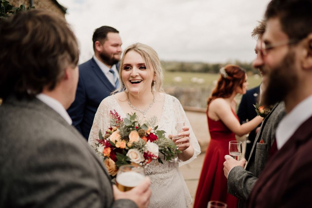 A joyful wedding reception moment outdoors with guests mingling and a beautiful bouquet of flowers.