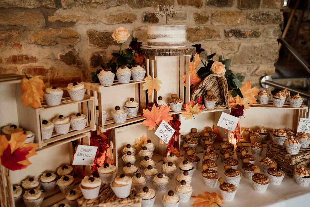 Rustic dessert display with cupcakes and autumn decorations on wooden crates.
