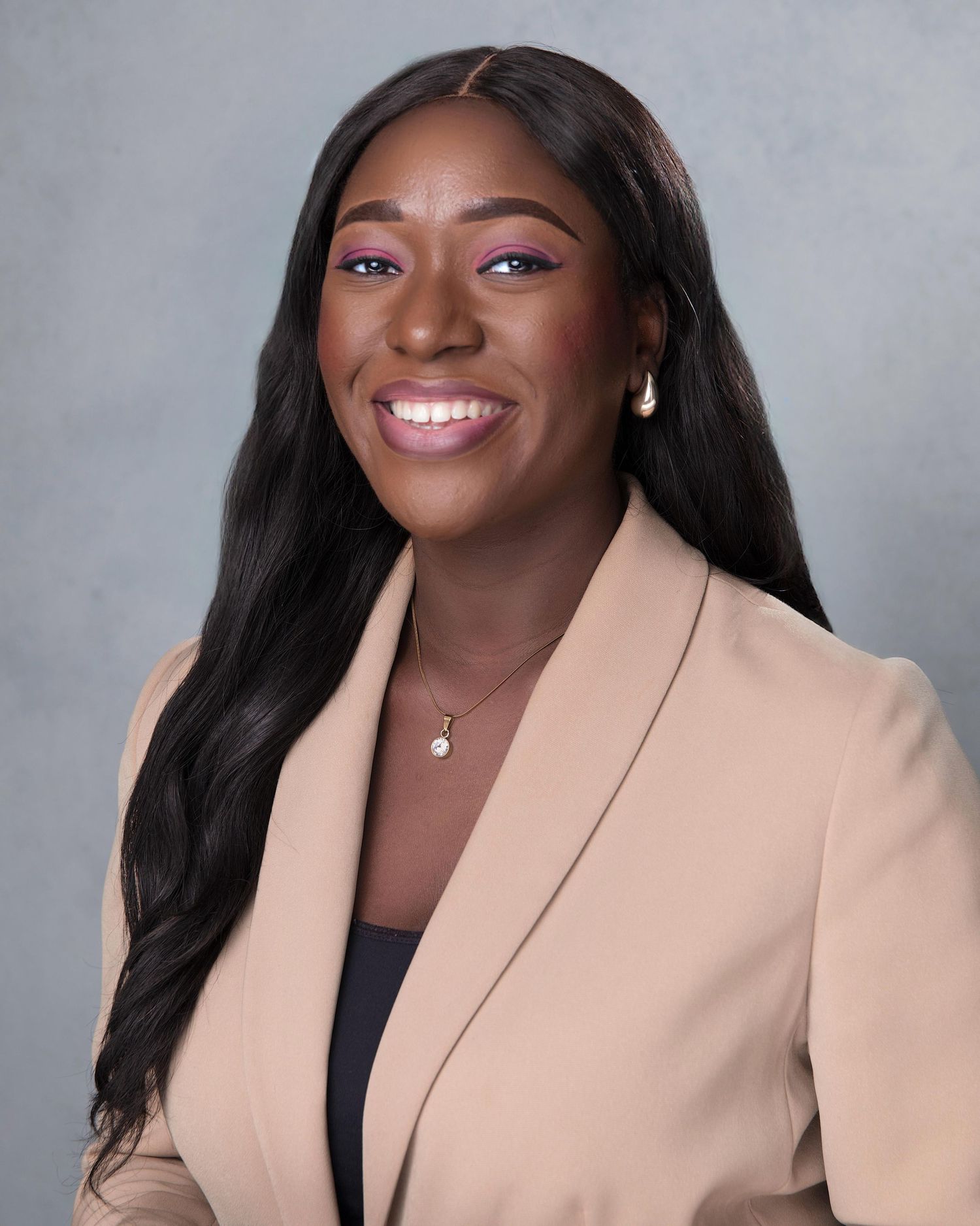 Felicia Damilola Badmus Headshot with a smile and wearing a brown suit jacket