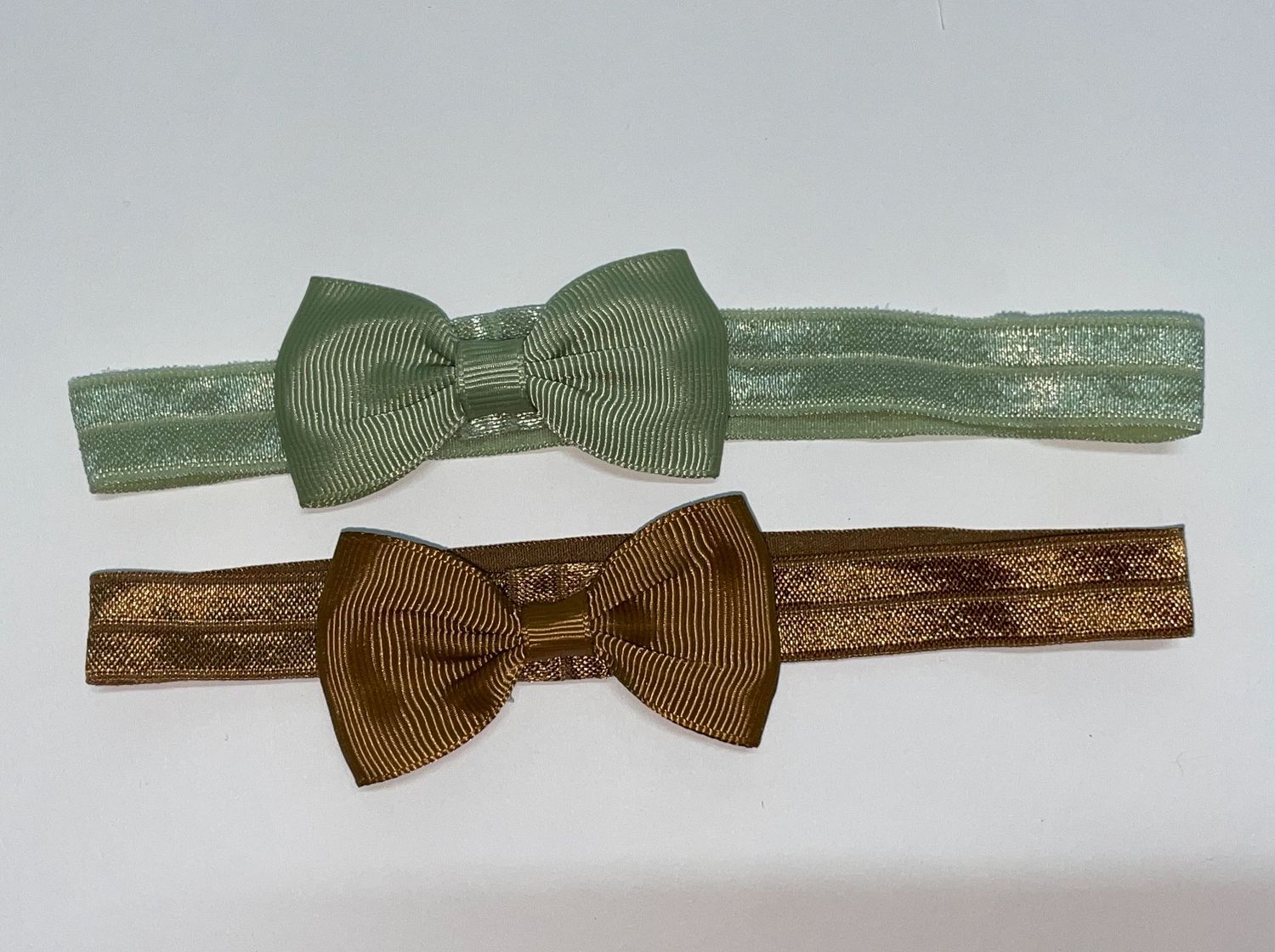 Three delicate bow ties in green and brown tones on thin bands.