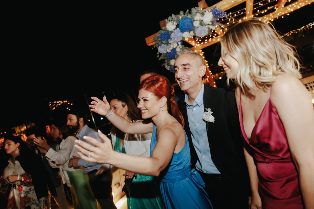 Party guests dance and celebrate at an evening reception with twinkling lights in the background.