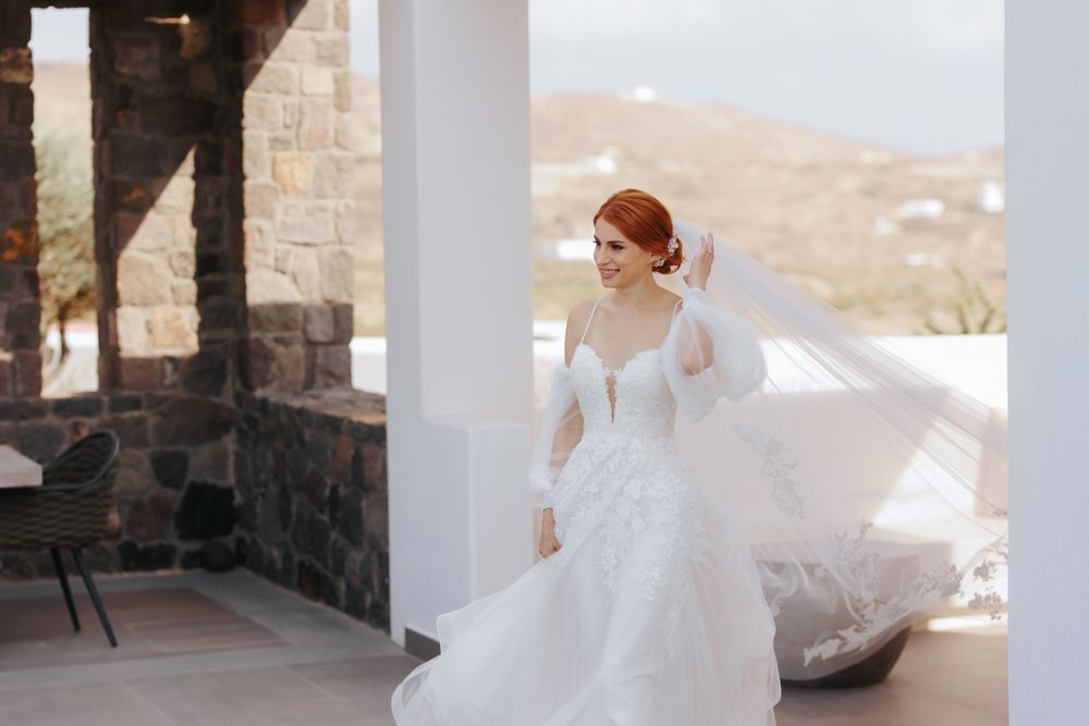 An elegant wedding dress with long sheer sleeves and intricate lace detailing on a covered porch with mountain views.