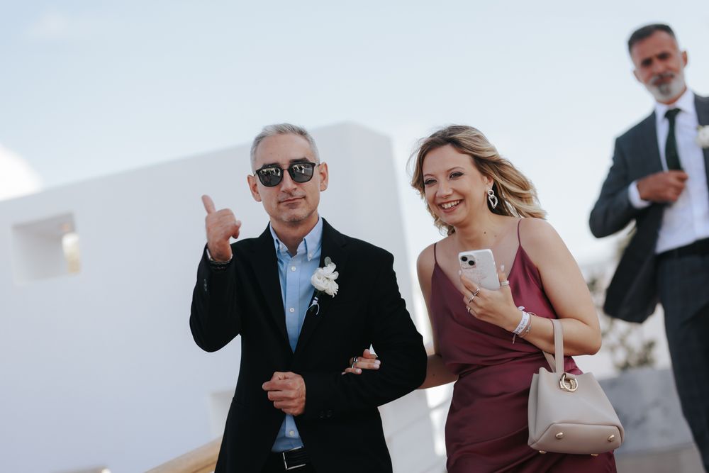 Guests walk arm-in-arm and laugh joyfully together during an elegant outdoor celebration.