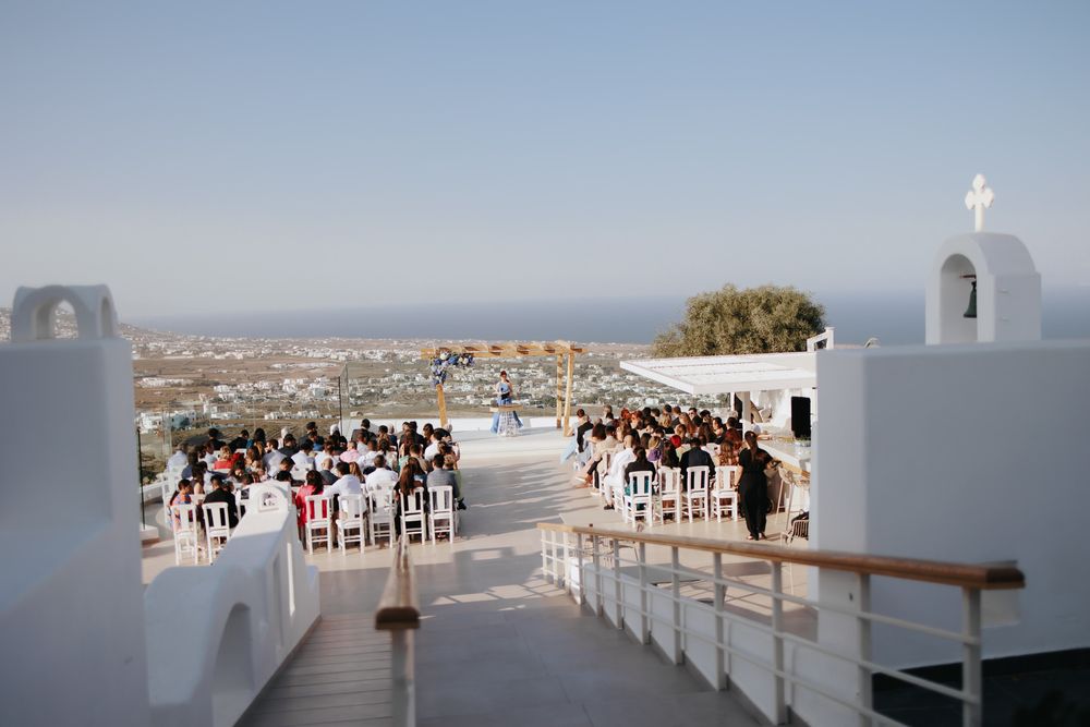 White-washed church steps overlooking an elegant outdoor wedding ceremony with scenic ocean views.
