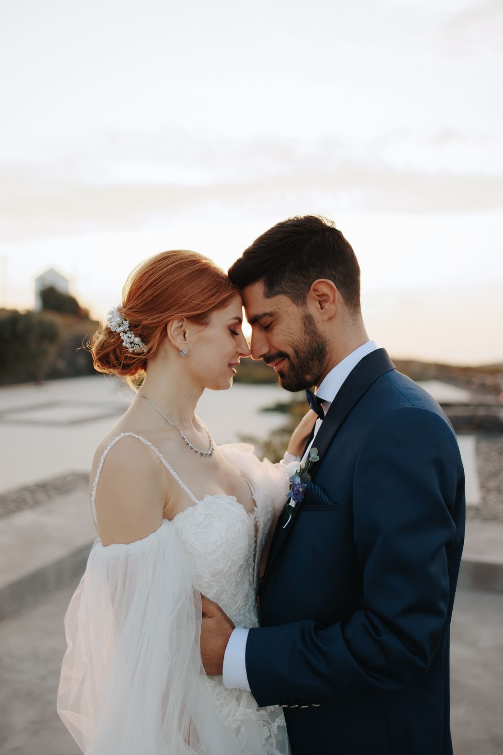 A romantic wedding portrait shows a tender moment between newlyweds at sunset.