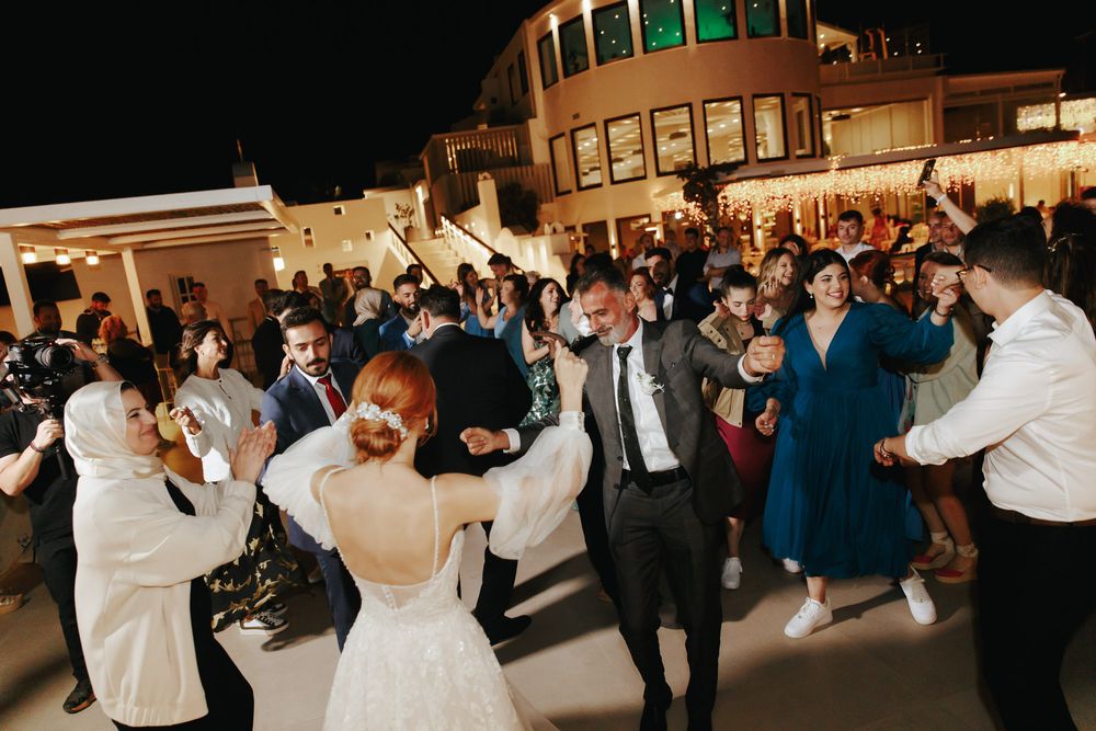 Lively wedding reception dance party with guests celebrating on an outdoor terrace at night.