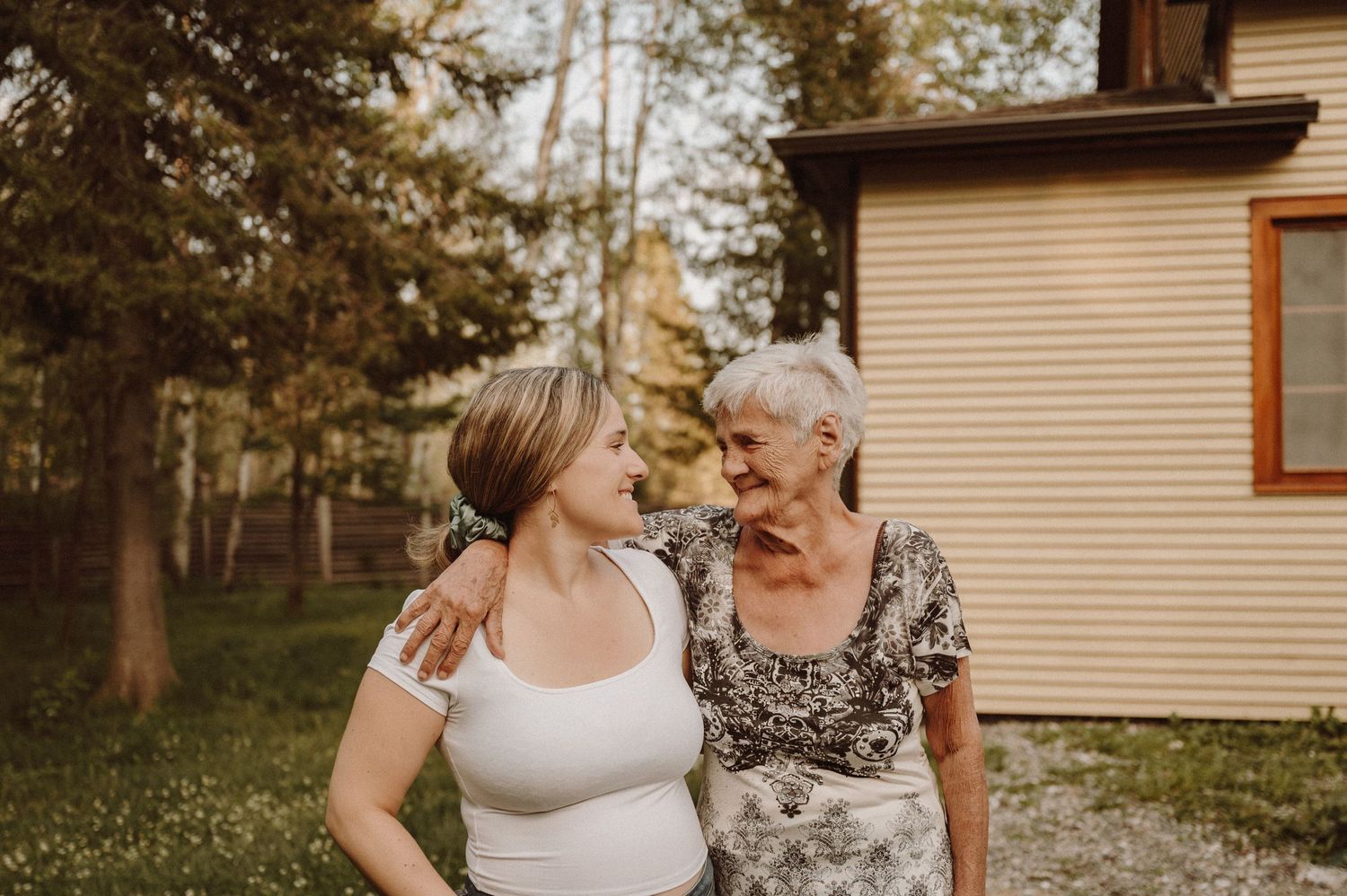 Two people sharing a tender moment while standing in front of a house.