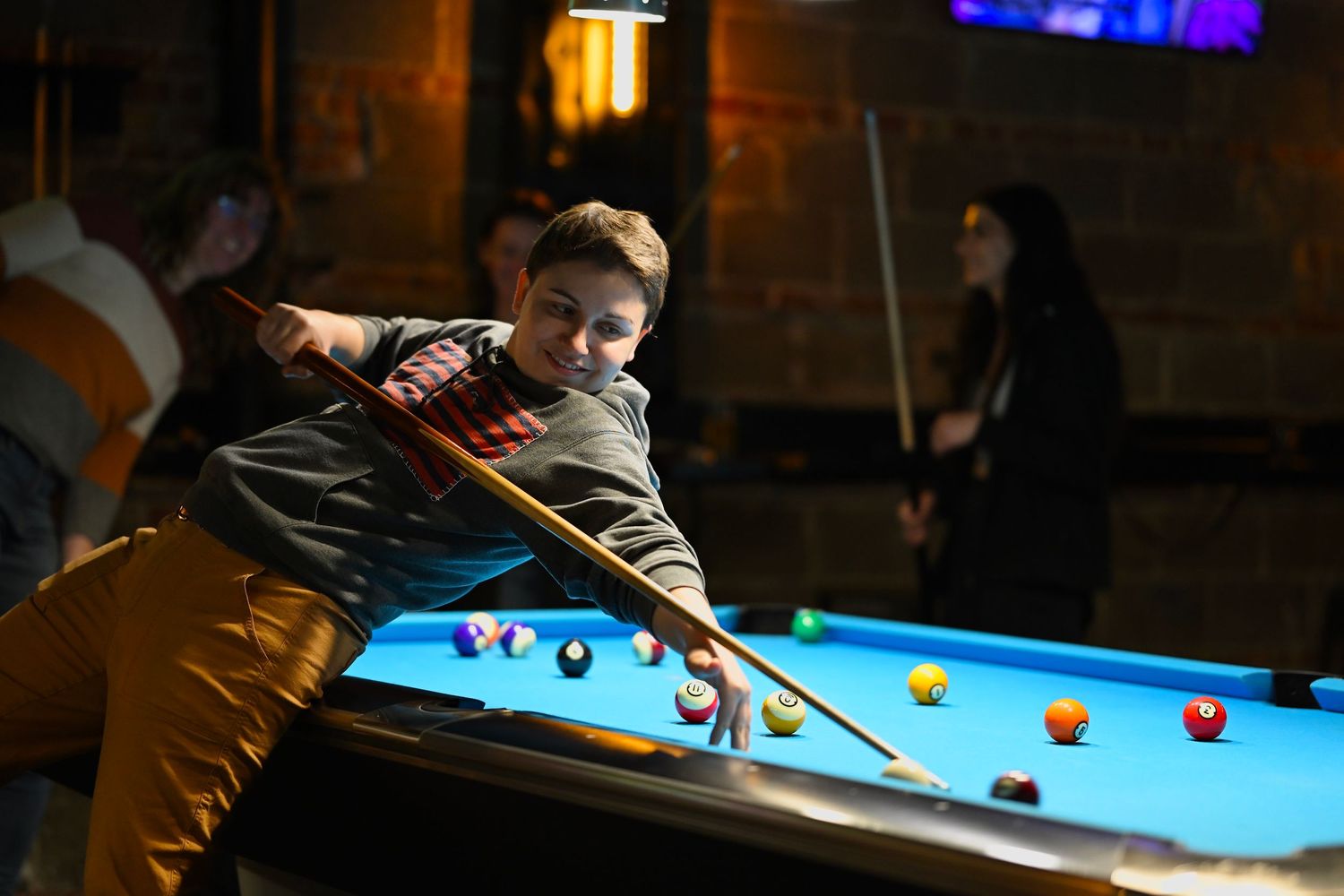 A player lines up their shot and holds the cue stick creatively in a game of pool at Surge Billiards in Chicago