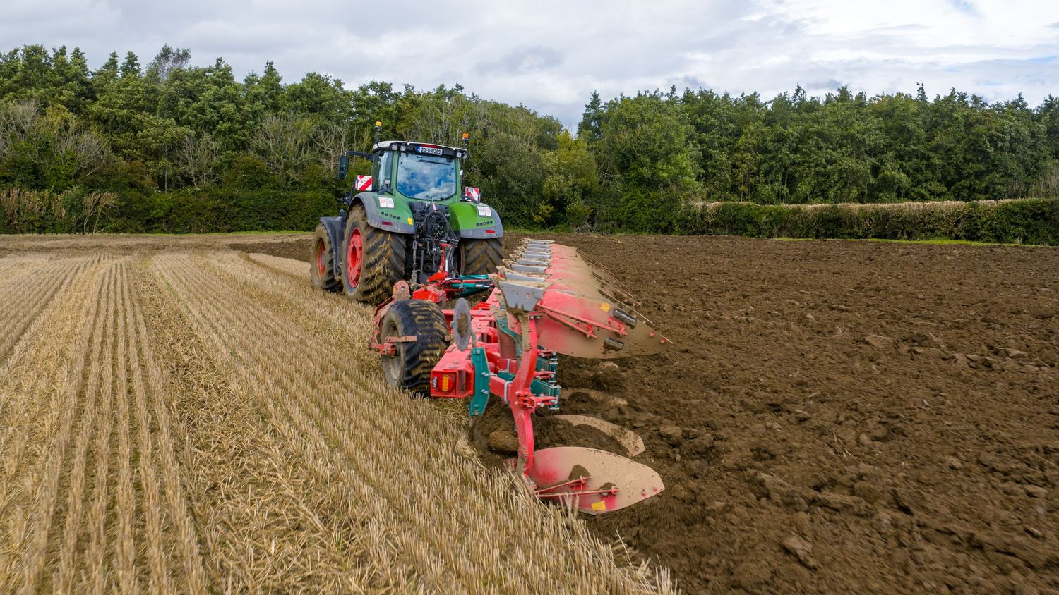 Green John Deere tractor with irrigation equipment in grassy field.