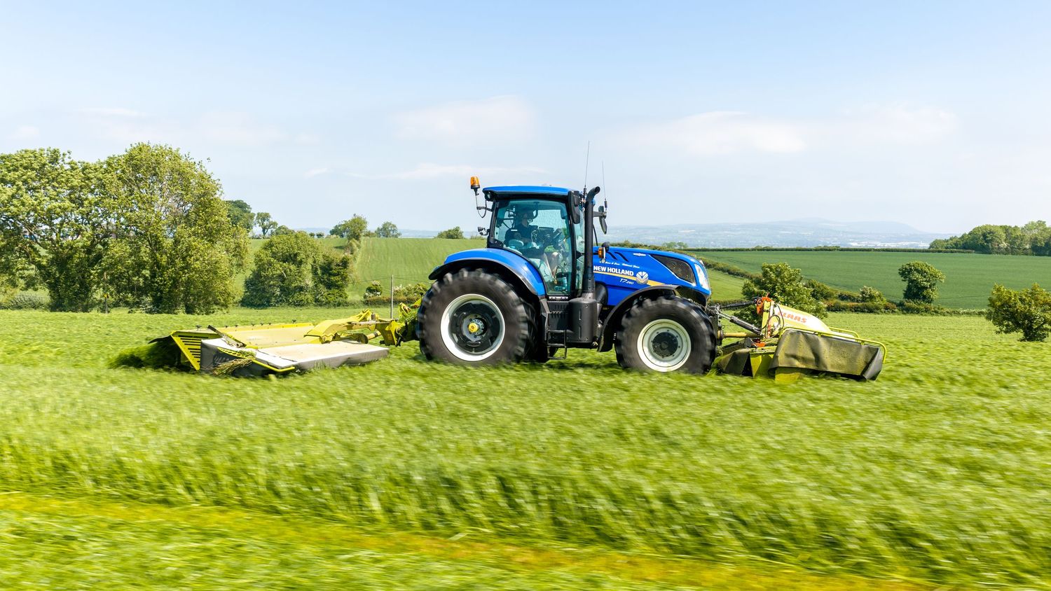 Green John Deere tractor with irrigation equipment in grassy field.