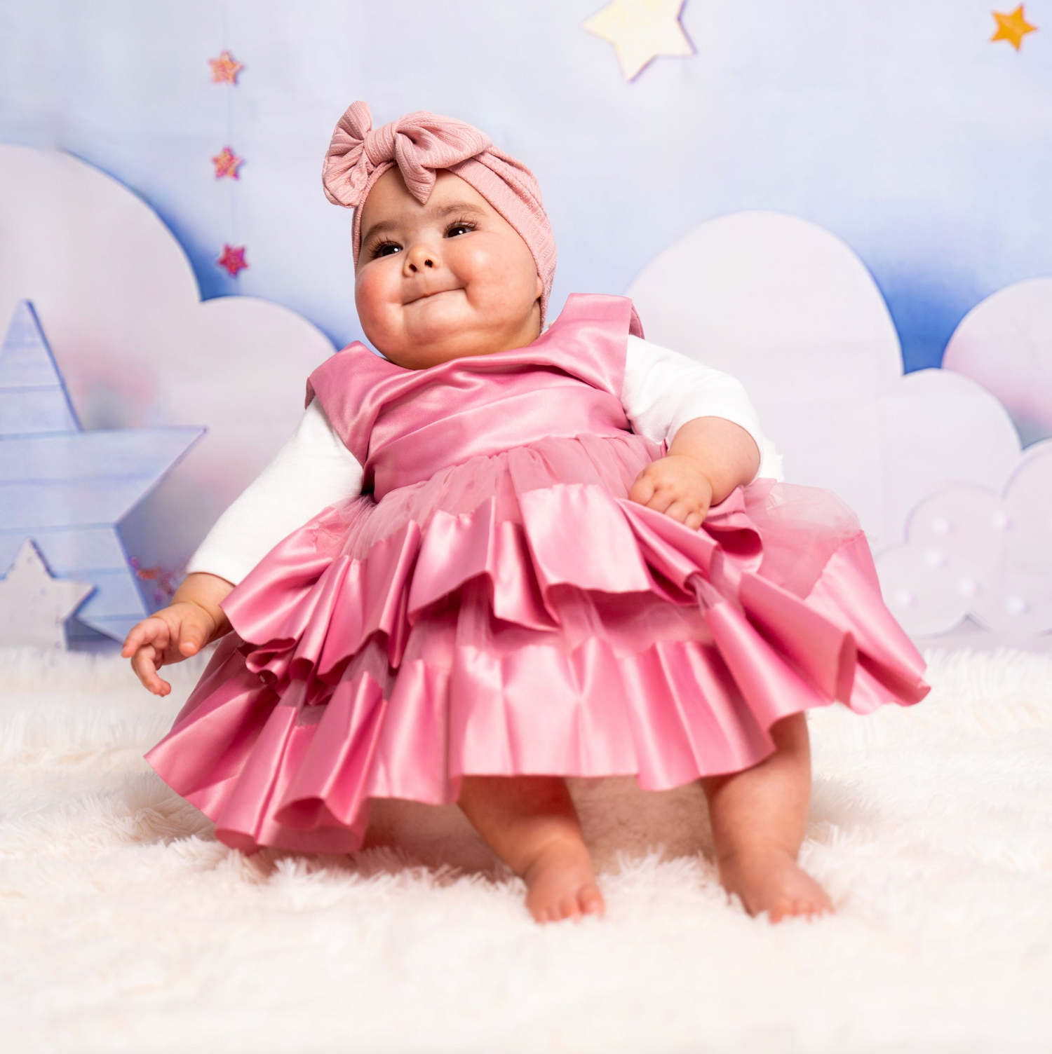 Pink tulle dress photoshoot setup with stars and cloud decorations on white background.