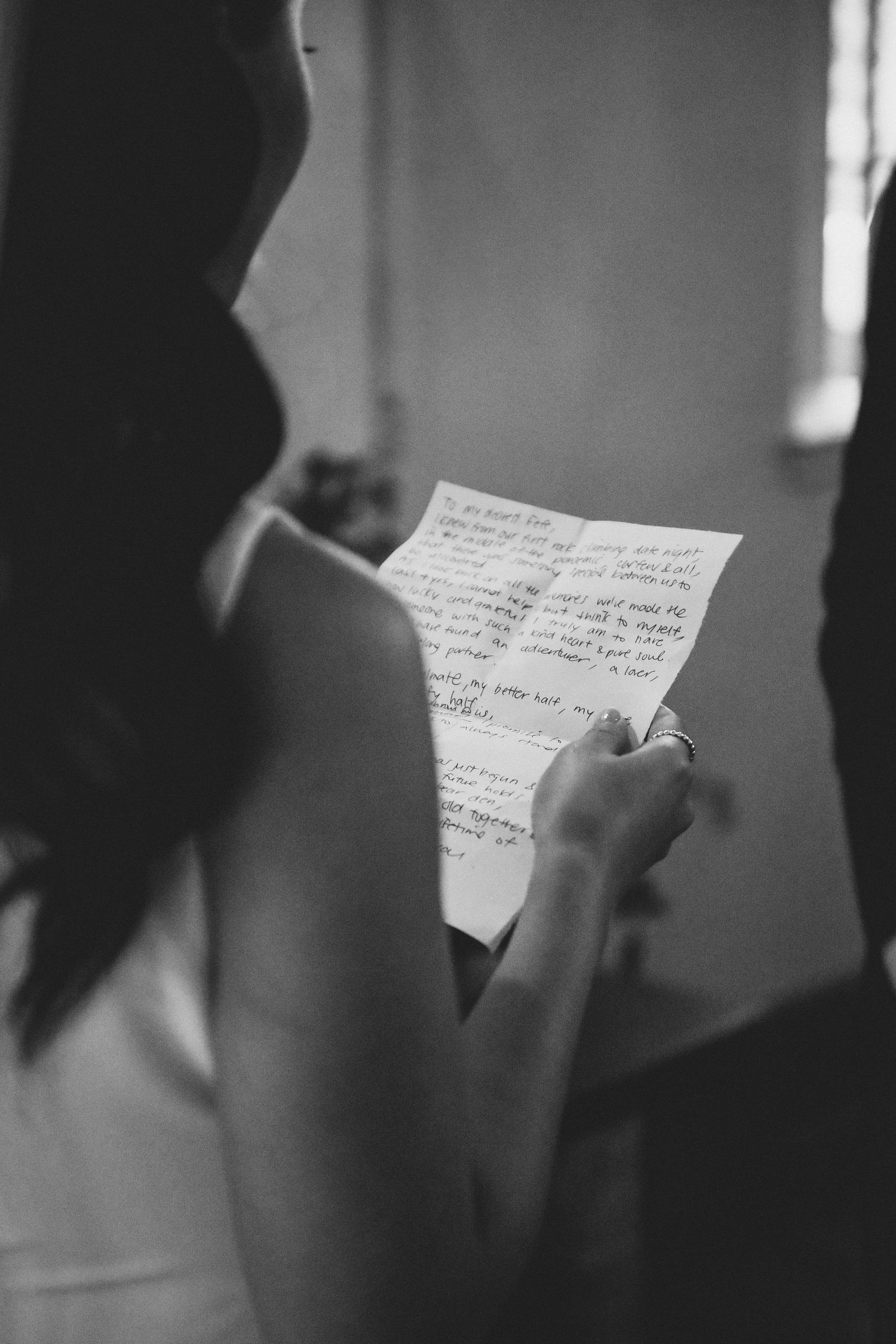 A black and white image shows hands holding handwritten notes or letters in a series of sequential shots.