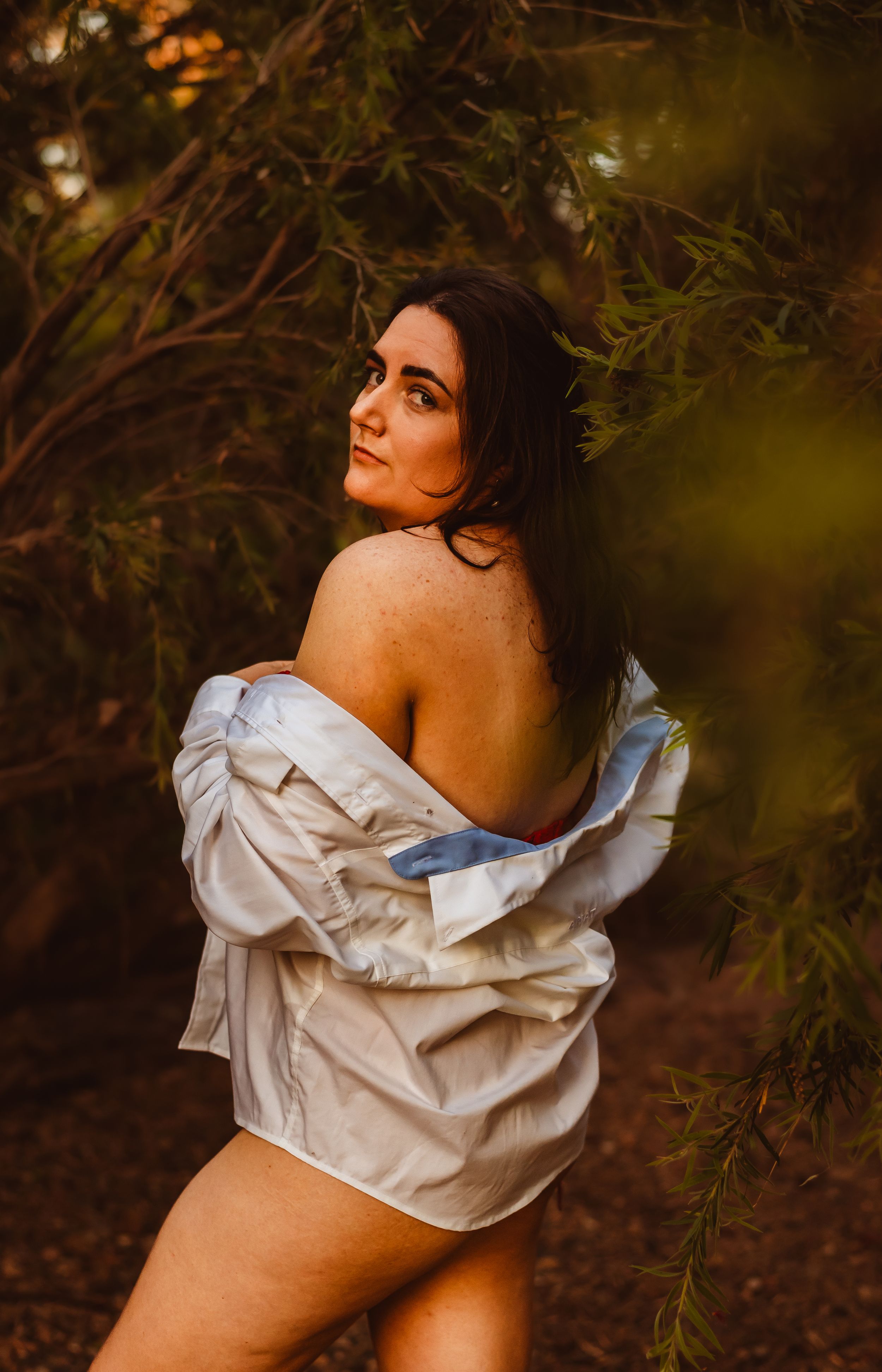 Dramatic outdoor boudoir photography with natural foliage elements.