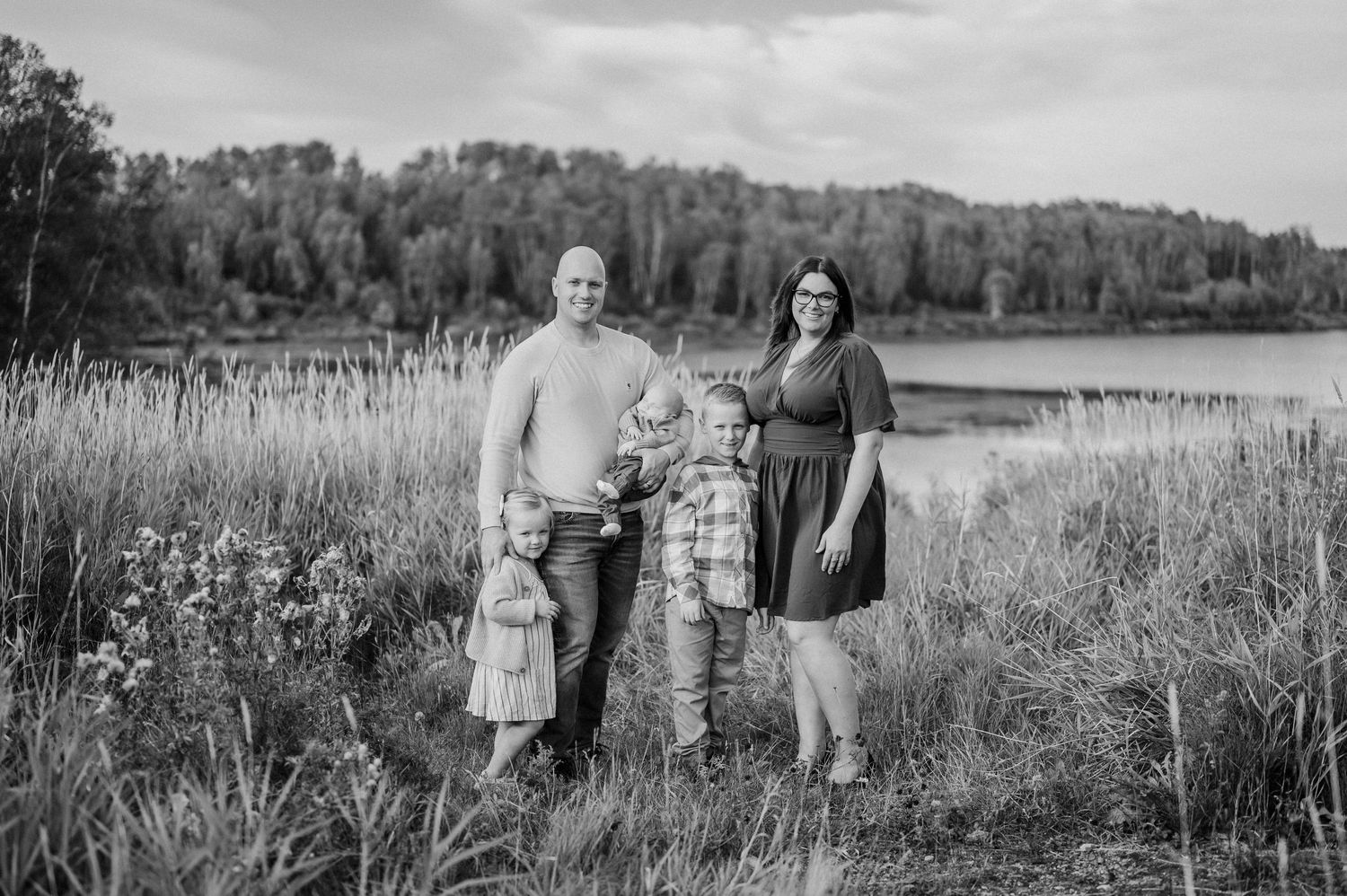 Black and white portrait of a family in a serene natural setting.