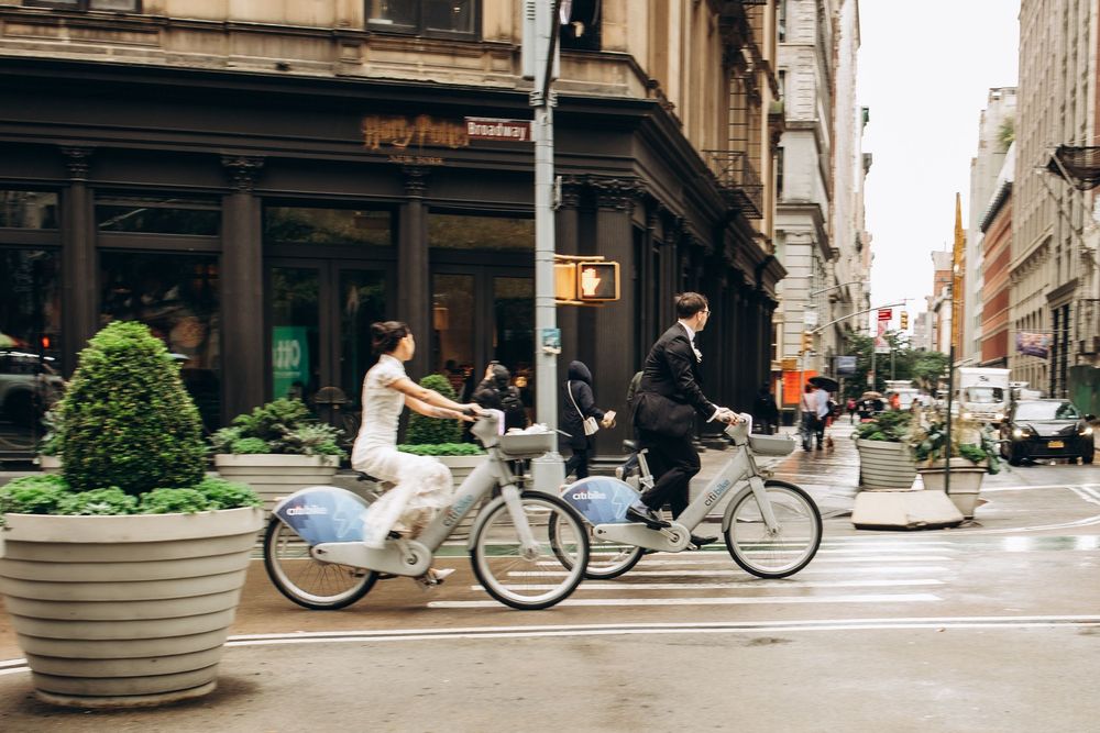 A series of connected urban street scenes showing cyclists, concrete planters, and city buildings in muted tones.