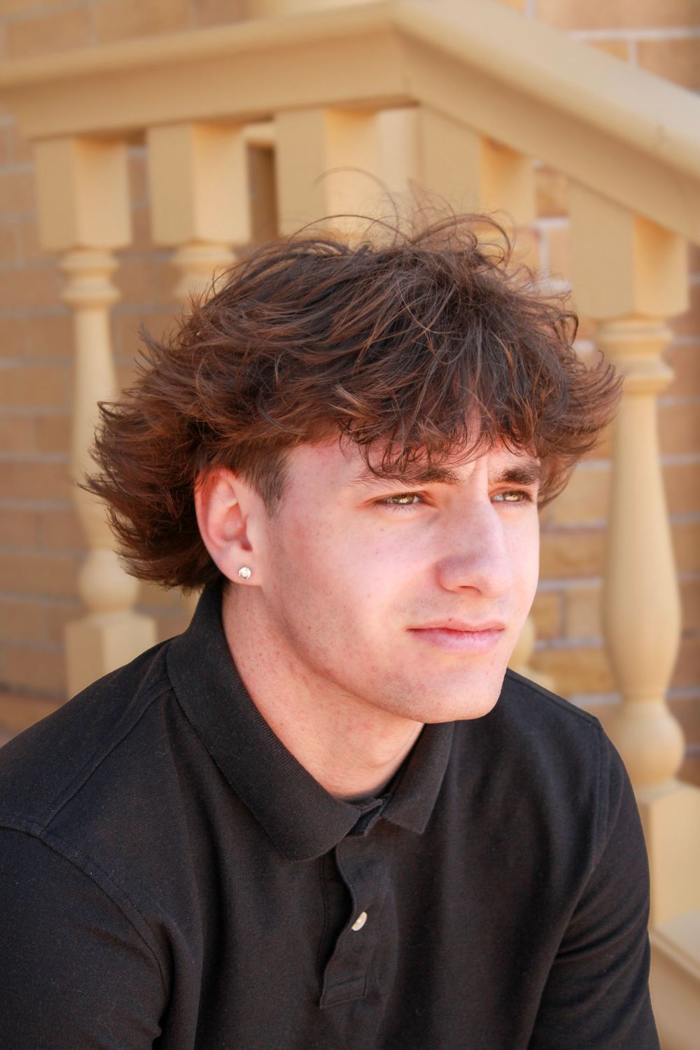Portrait with beige architectural columns in background and person in dark polo.