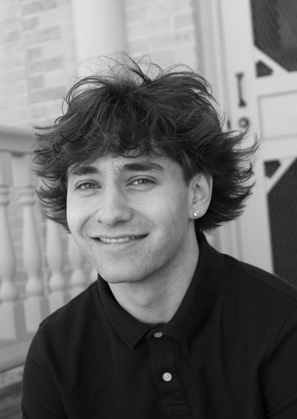 Black and white portrait with architectural details showing person in dark polo shirt.