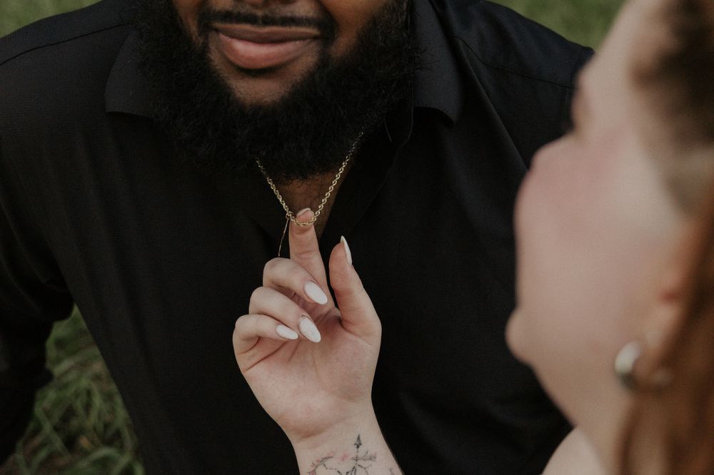 Close-up shot of hands holding a delicate necklace pendant during an outdoor photoshoot.