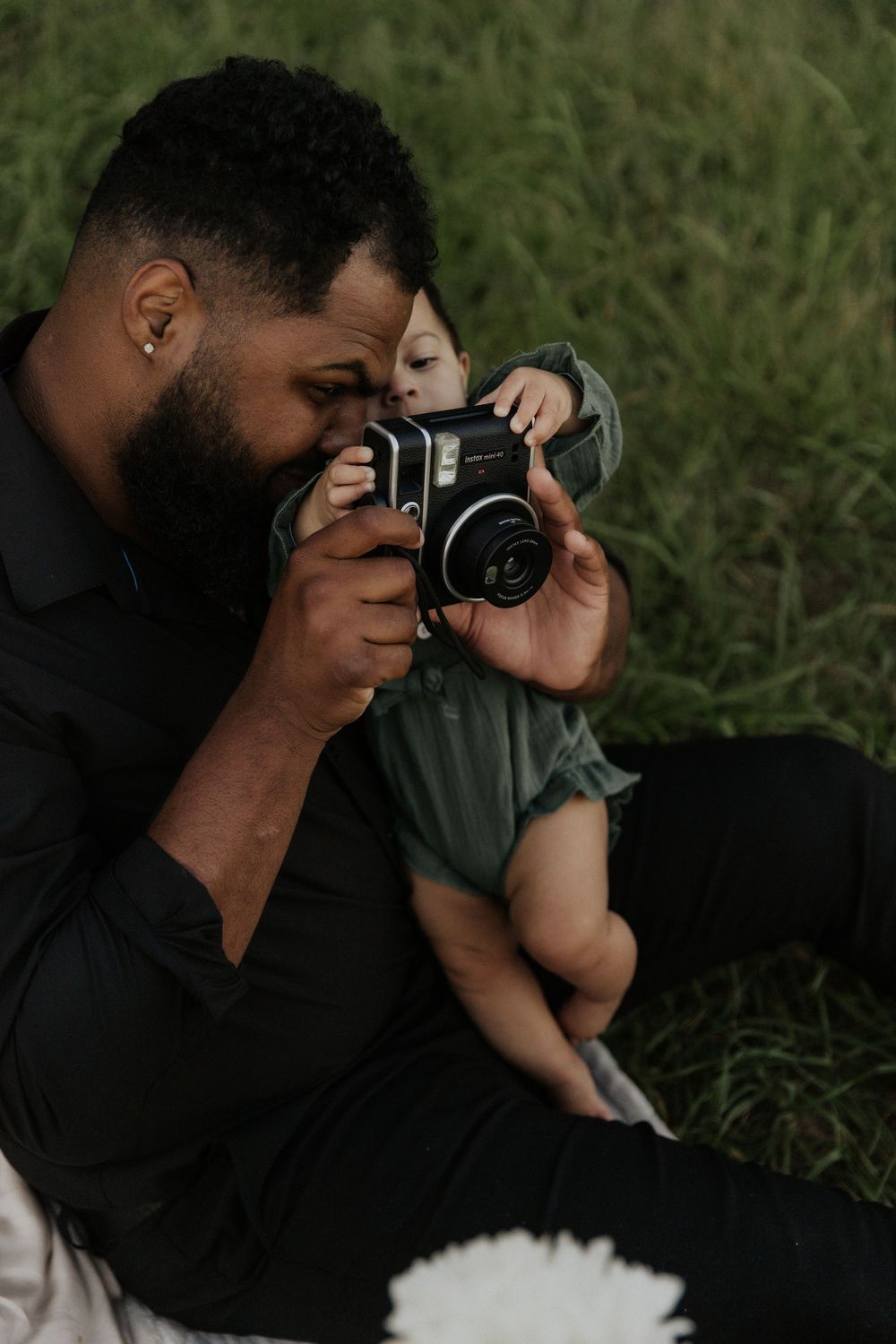Two people share a moment looking through vintage camera lens outdoors.