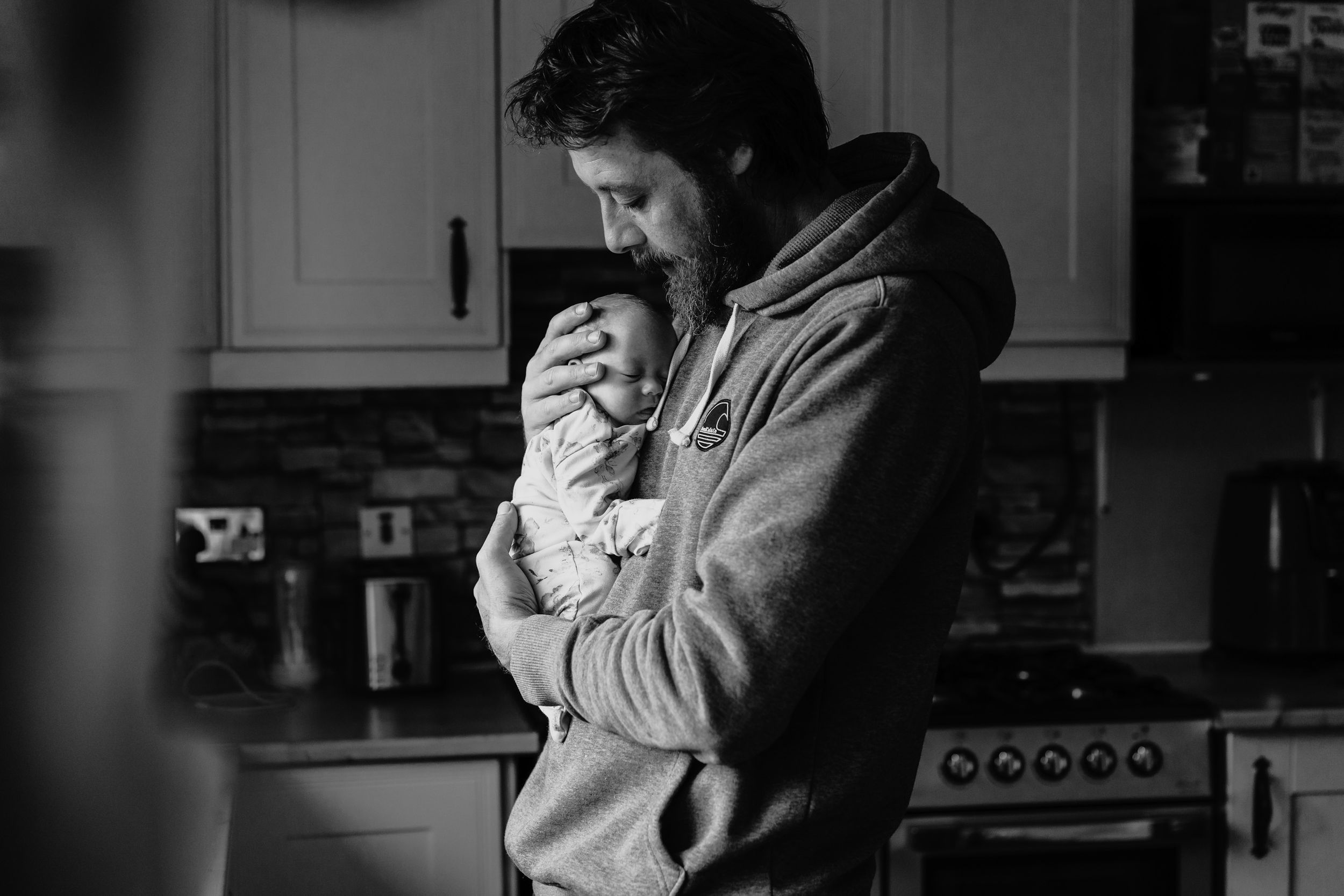 A tender black and white moment captured in a home kitchen setting.