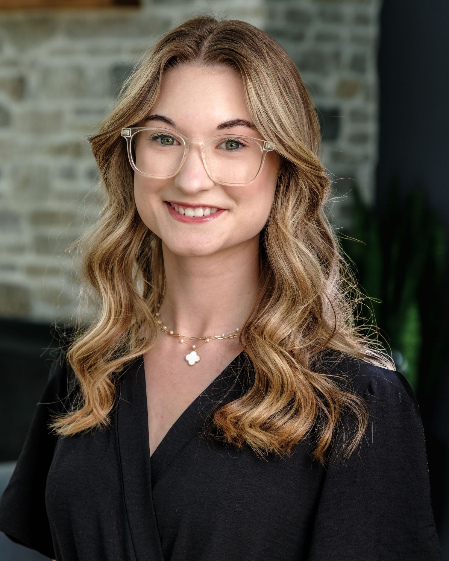 Person wearing glasses and a bright blue zip-up fleece with Calvary branding smiles warmly against dark background.
